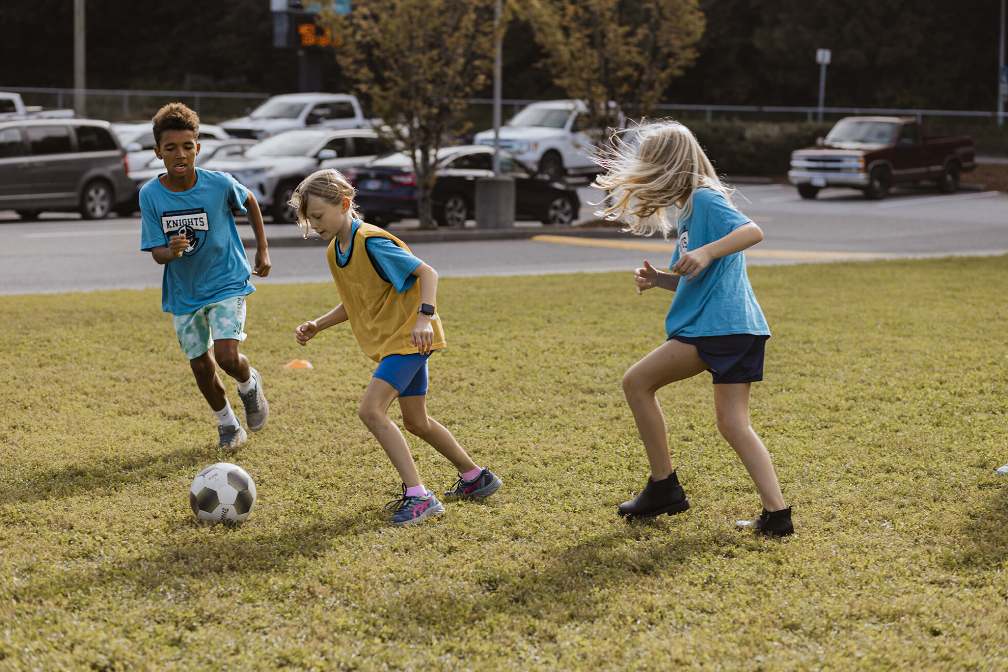 Three ACS middle school students play soccer in the front field
